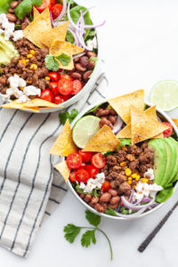 This delicious and easy healthy taco salad recipe is made with a simple salsa dressing, extra lean ground beef, veggies galore, corn, beans, dairy free cheese and quick baked tortilla chips. It’s a clean eating recipe that is perfect for meal prep and a filling lunch or dinner!