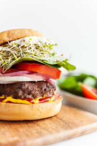 Close up of Air fryer burger with sprouts, lettuce, tomatoes, ketchup and mustard